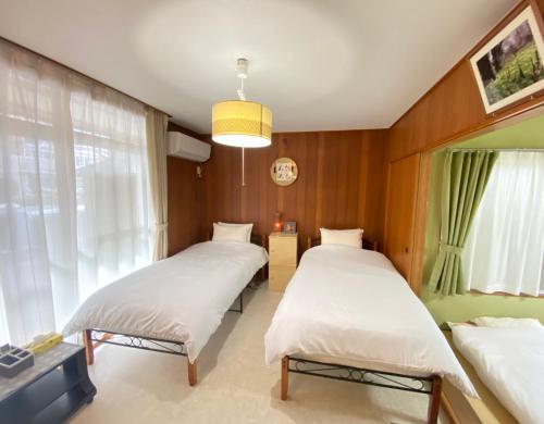 2 Betten in einem holzvertäfelten Zimmer in der Unterkunft 浜町小院 Guest House in Takamatsu