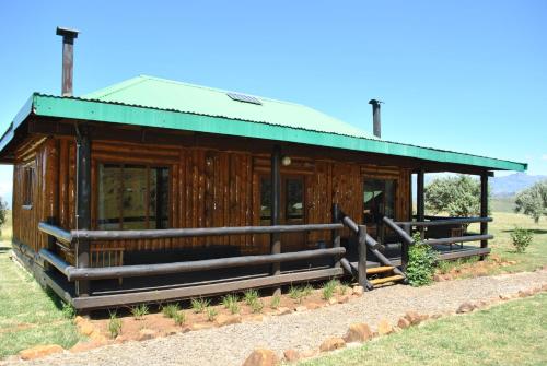 a large wooden building with a green roof at Greenfire Drakensberg Lodge in Bonjaneni