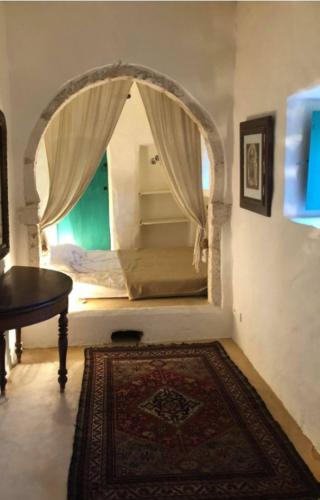 um quarto com uma arcada com uma cama em Dar zmen em Tunes