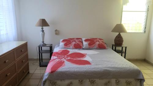 1 dormitorio con 1 cama con 2 almohadas rojas y blancas en CASA BETTY COSTAMBAR en San Felipe de Puerto Plata