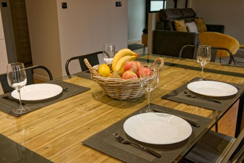 a table with plates and a basket of fruit on it at Les balcons de Cuttura 1 & SPA chez Ô JurassiK in Cuttura