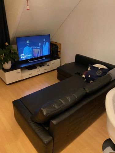 un sofá de cuero negro en la sala de estar con TV de pantalla plana en Nice Private Room in Shared Apartment - 2er WG, en Wiesbaden