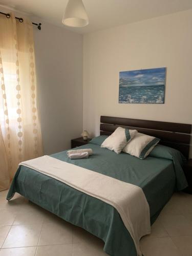 Pizzo Beach Club Apartment Ginevra في بيتسو: غرفة نوم مع سرير مع لحاف أخضر