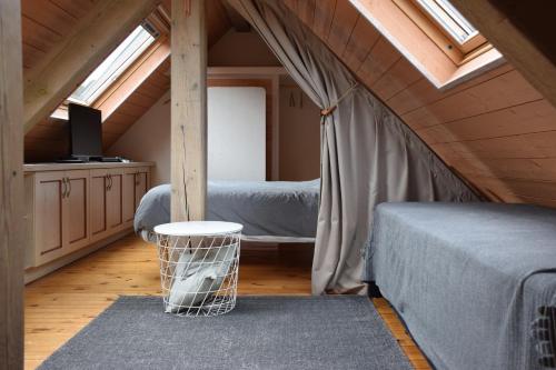 um quarto no sótão com uma cama, uma secretária e janelas em Petit duplex de charme sous les toits du Mont-Dore em Le Mont-Dore