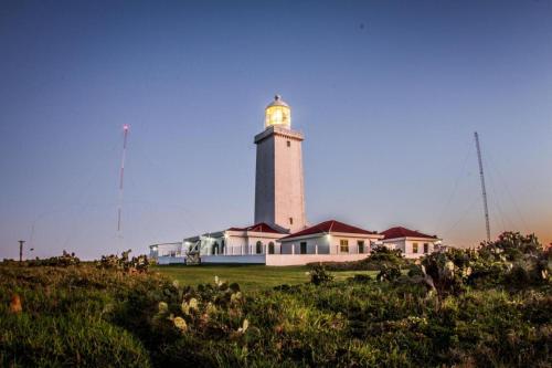 a lighthouse sitting on top of a green field at Casas da Dalma in Farol de Santa Marta