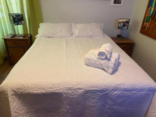 Una cama con sábanas blancas y toallas. en La Casa de Carlitos, en San José de Maipo