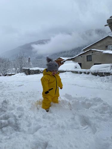 a child is standing in the snow at Guesthouse SHAMPRIANI in Mestia