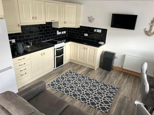 a kitchen with white cabinets and a black tile wall at The Dingle Galley in Dingle