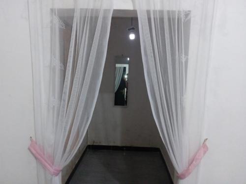 a hallway with white curtains in a room at Tui Homestay in Plambi