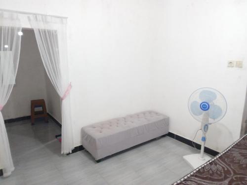 a white room with a bed and a fan at Tui Homestay in Plambi
