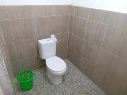 a bathroom with a toilet and a green trash can at Tui Homestay in Plambi