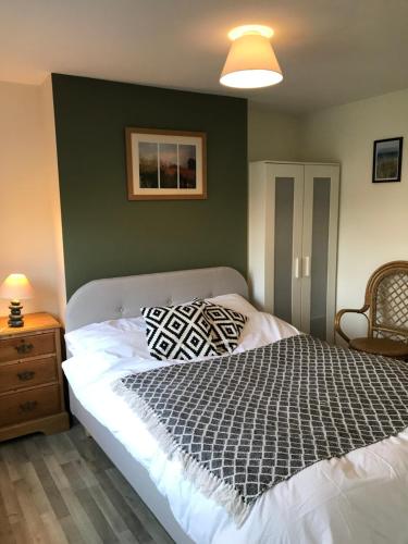 a bedroom with a bed and a green wall at Cosy 3 bedroom house close to beach in Lowestoft