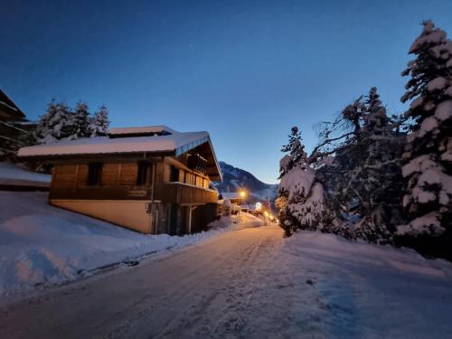 a snow covered road in front of a cabin at Chalet le Petit Ramoneur in Châtel