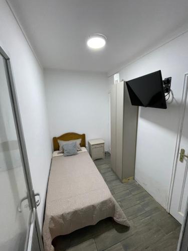 um pequeno quarto com uma cama e uma televisão em Habitación pleno centro de Viña del Mar con entrada y baño independiente privado. r em Viña del Mar