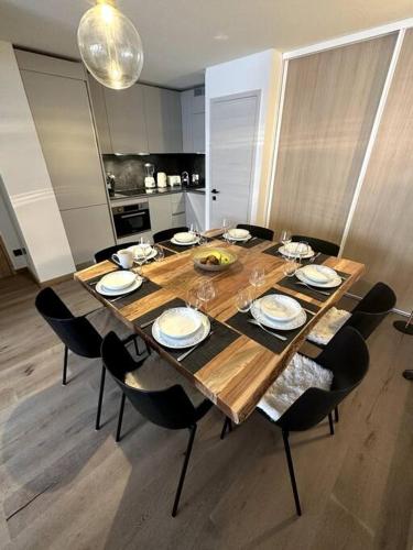 une table à manger avec des chaises et une grande table en bois dans l'établissement T3 neuf Courchevel 1650 Domaine de l’Ariondaz, à Courchevel
