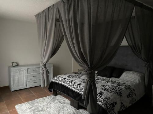 1 dormitorio con cama con dosel, cortinas y alfombra en Cabañas La lunada, en Las Palomas
