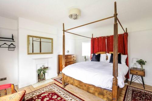 a bedroom with a canopy bed with a red curtain at Duke of York Cottage, Port Sunlight - Stanley-Stays in Wirral