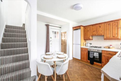 a kitchen with a table and white chairs and a staircase at Duke of York Cottage, Port Sunlight - Stanley-Stays in Wirral