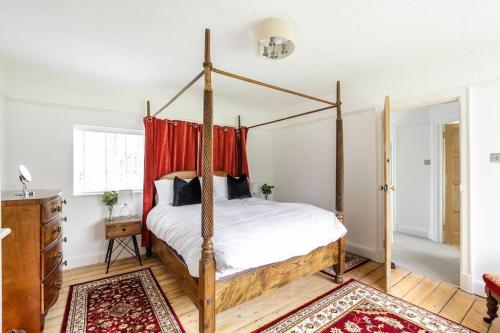 1 dormitorio con cama con dosel y cortinas rojas en Duke of York Cottage, Port Sunlight en Wirral