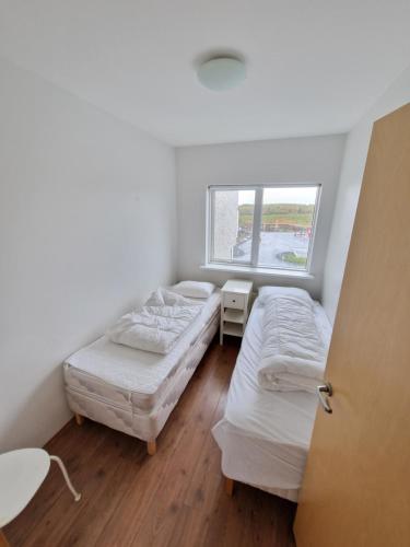 two beds in a room with a window at Eyjasol Apartments in Reykjavík