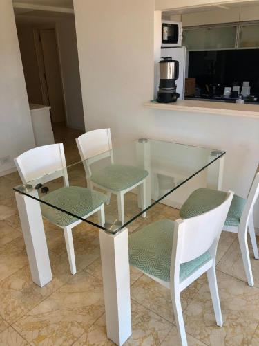 a glass table with four chairs and a kitchen at deptomardel_playa in Mar del Plata