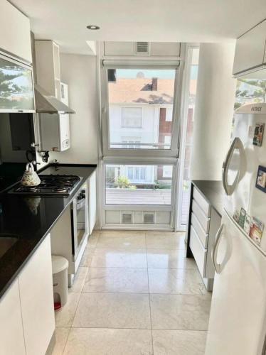 a white kitchen with a large window and a stove at deptomardel_playa in Mar del Plata