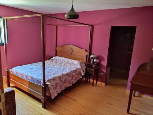 une chambre avec un lit et un mur rose dans l'établissement Casa con encanto en el campo, à Pontevedra