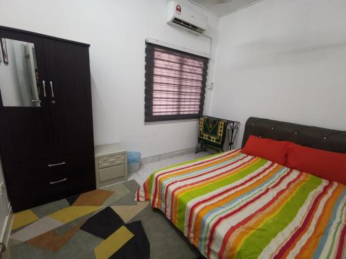 Kampong ChinchangにあるNASYA HOMESTAY BANDAR ENSTEKのベッドルーム1室(カラフルなストライプ毛布付きのベッド1台付)