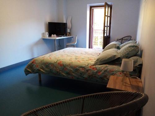 a bedroom with a bed and a television and a chair at Auberge du Marronnier in Belmont-sur-Rance