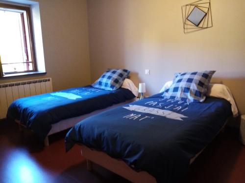 two beds in a room with blue comforters at Auberge du Marronnier in Belmont-sur-Rance
