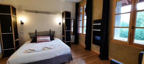 a bedroom with a bed in a room with windows at Transhumance & cie, Auberge, Appartements & SPA in Bedous