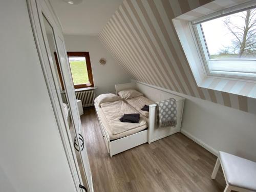 a small attic room with a bed and a window at Hus am Diek in Friedrichskoog