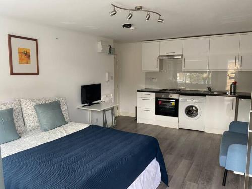 um quarto com uma cama azul e uma cozinha em Studio Apartment in Seven Sisters em Londres