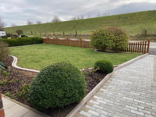 a garden with a fence and a lawn with bushes at Hus am Diek in Friedrichskoog
