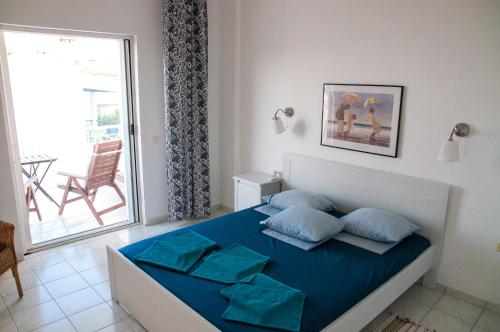 a bedroom with a bed with blue sheets and a window at Alexger Gerakini Beach house view in Gerakini