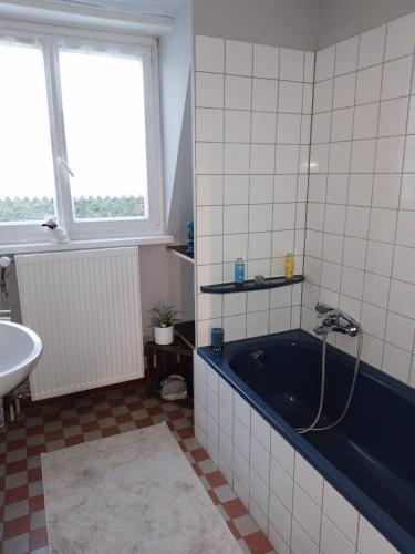 La salle de bains est pourvue d'une baignoire bleue et d'un lavabo. dans l'établissement Le tribunal alsacien, à Bouxwiller