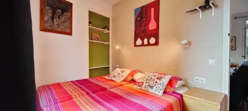 una piccola camera da letto con un letto con lenzuola colorate di Casa con jardín a 30 metros de la playa. VC. a Palamós
