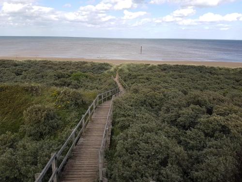 a wooden staircase leading to a beach with the ocean at Tide Away Anderby Creek in Anderby