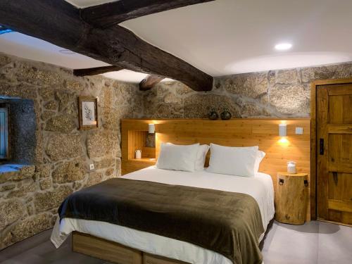 a bedroom with a large bed in a stone wall at Quinta das Bollótâs in Travassós