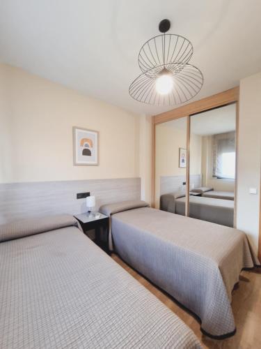 Habitación de hotel con 2 camas y lámpara de araña. en Apartamentos Salvia 4 en Madrid