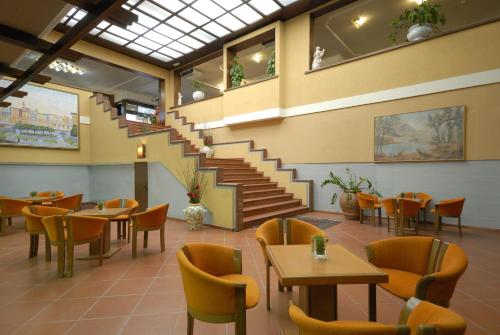 a restaurant with a staircase and tables and chairs at Hotel Delta Florence in Calenzano