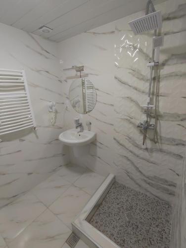 a white bathroom with a sink and a mirror at Happy Stay Hotel in Kutaisi