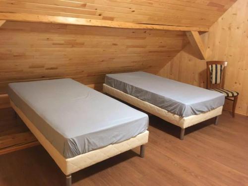 twee bedden in een kamer met houten wanden bij Saules Rats Apartamenti in Madona