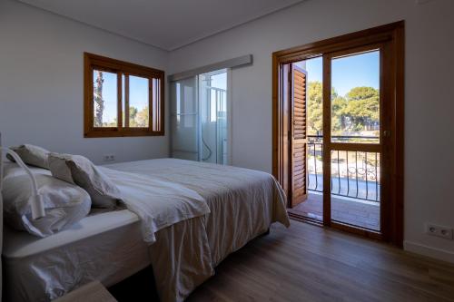 マニセスにあるVilla Huerta 1 Manises, jacuzzi, sauna, piscinaのベッドとガラスの引き戸のある寝室