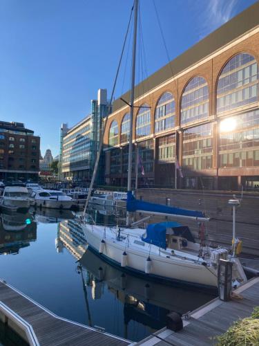 un bateau amarré dans un port de plaisance en face d'un bâtiment dans l'établissement Entire Boat at St Katherine Docks 2 Available select using room options, à Londres