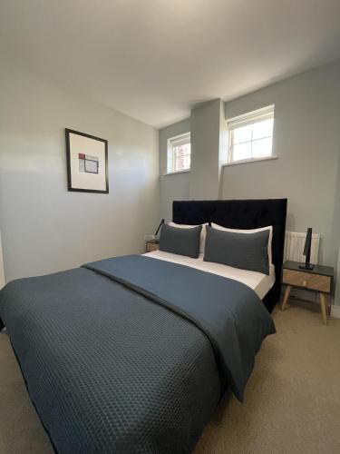 a bedroom with a large bed and two windows at Luxurious Private One Bedroom Apartment in Braintree with Free Parking Near City Centre in Braintree