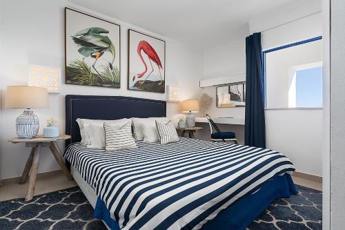 ein Schlafzimmer mit einem Bett mit einer blau-weißen gestreiften Decke in der Unterkunft Bianca Rocha in Portimão