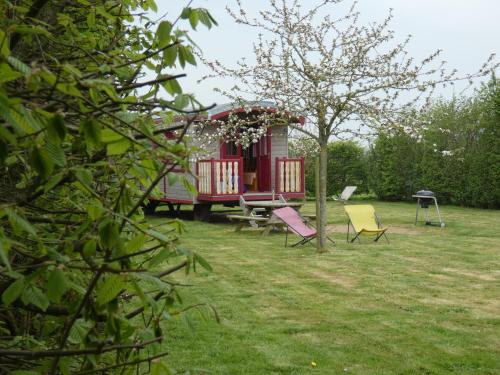 een huis met een picknicktafel en stoelen in een tuin bij La Roulotte des Matis in Cheux