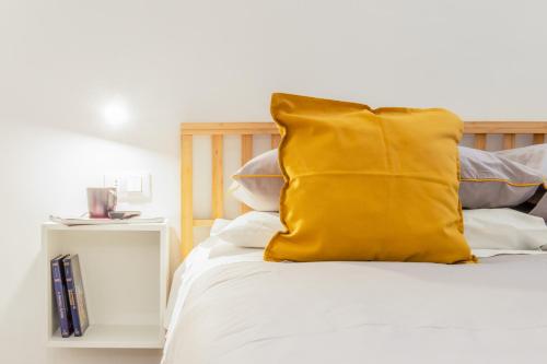 a yellow pillow sitting on top of a bed at Suite Apartments - Corso51 in Rimini