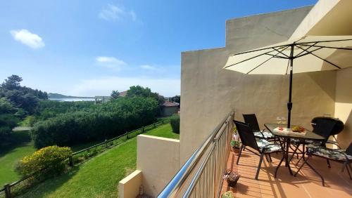 a balcony with a table and an umbrella at I 6 Goose Valley! Golf and more in Plettenberg Bay